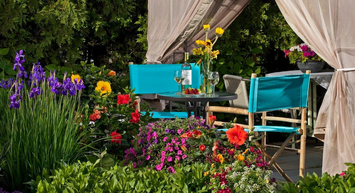 A cozy outdoor seating area adorned with vibrant flowers and a table set for drinks.