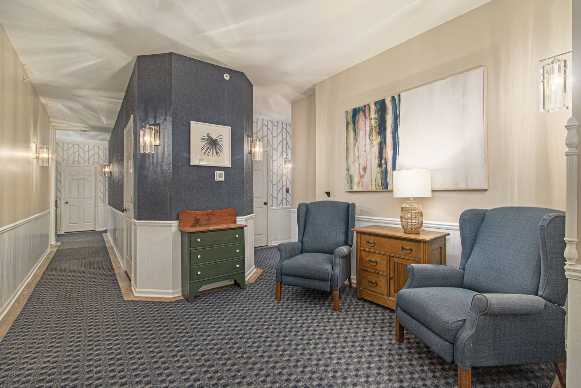 hallway with blue wall paper and two upholstered chairs