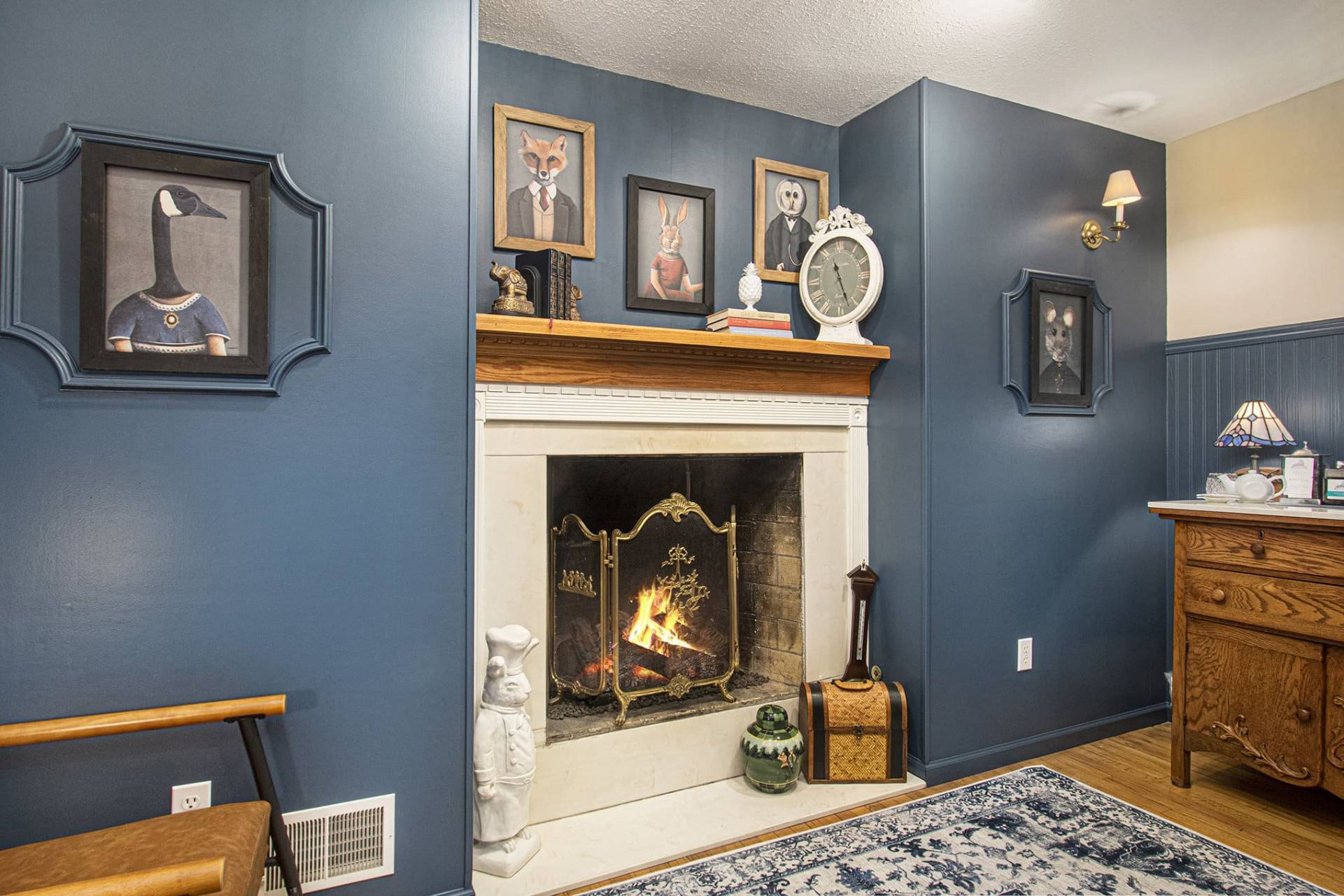 cozy fireplace surrounded by pictures of animals in formal attire.