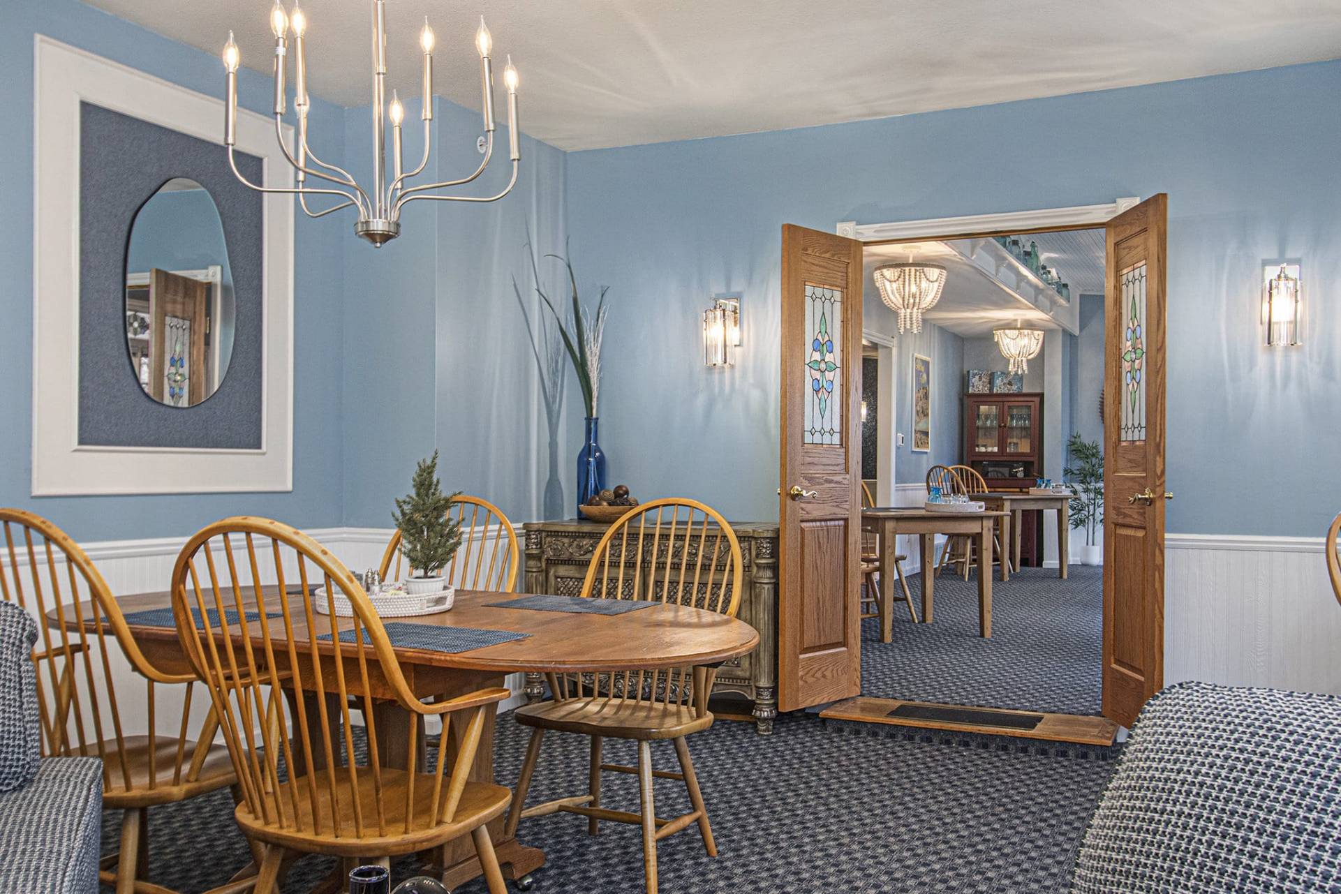 wood table and chairs in dining room with blue walls and blue carpet.